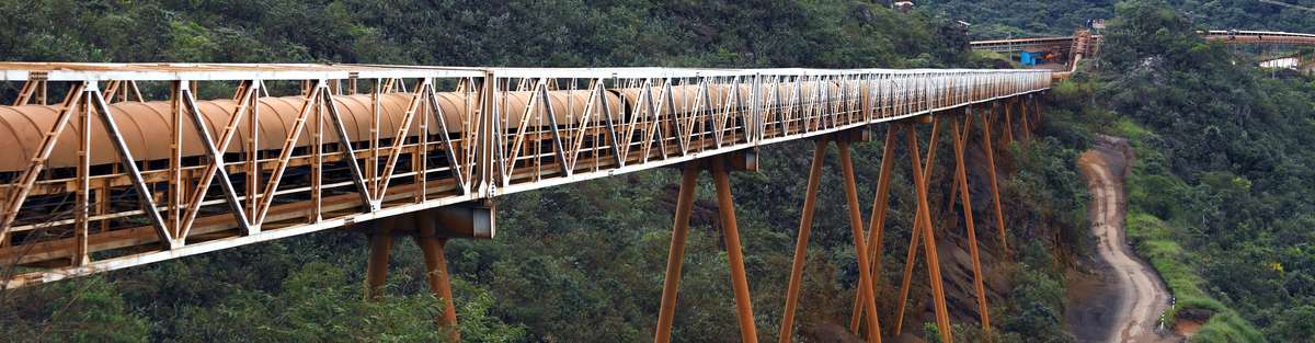 Pipeline leads over a high bridge in mountainous terrain.