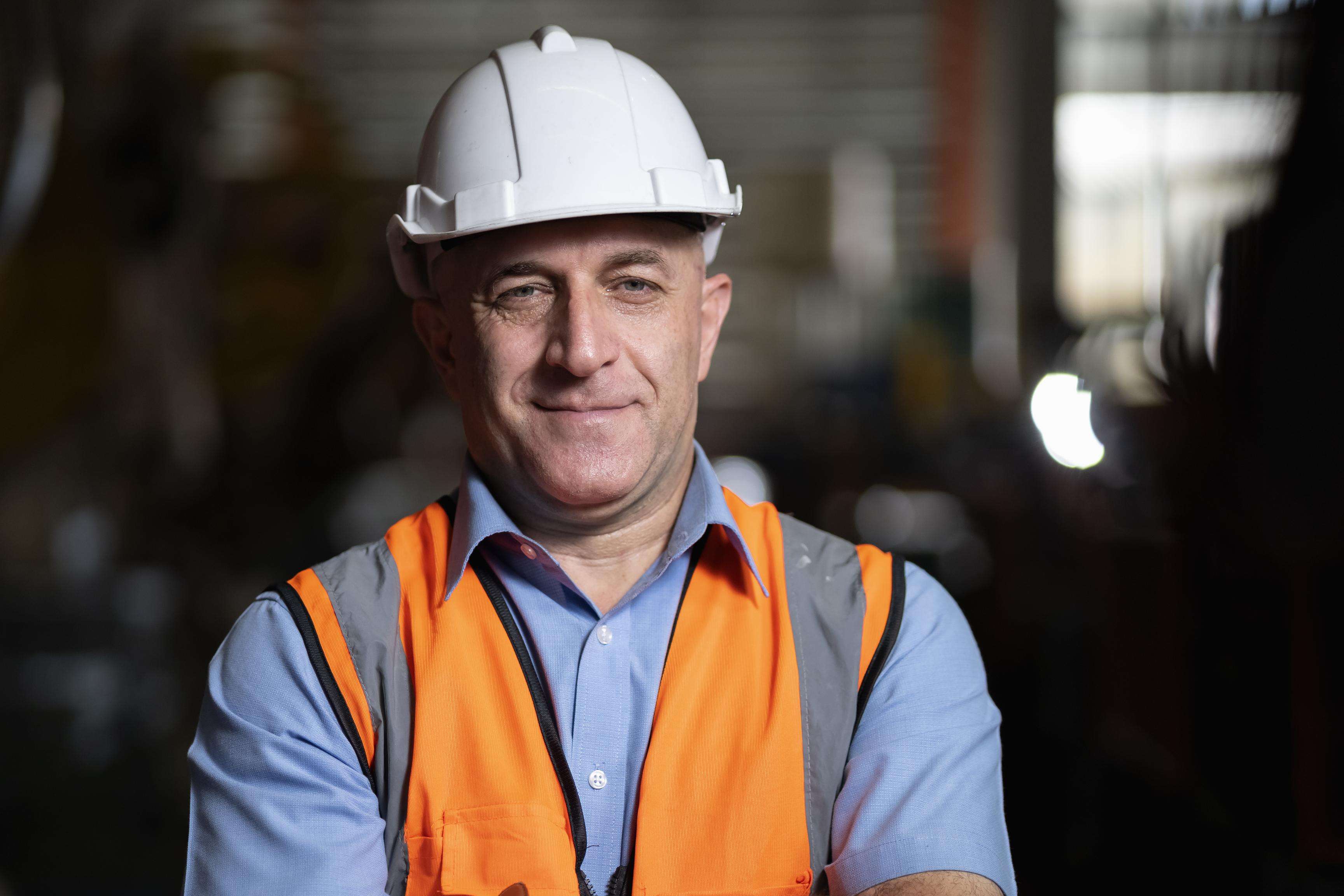 Man wearing a short-sleeved shirt, a safety vest and a safety helmet.