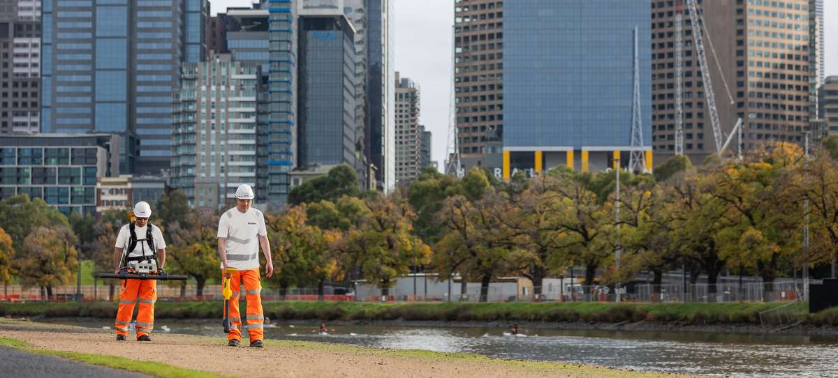Two ROSEN employees during a Large Stand-Off Magnetometry (LSM) survey in front of a skyline.