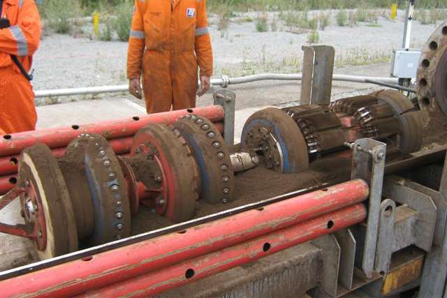 Dirty dual module cleaning pig at the receiver site with technicians in background.