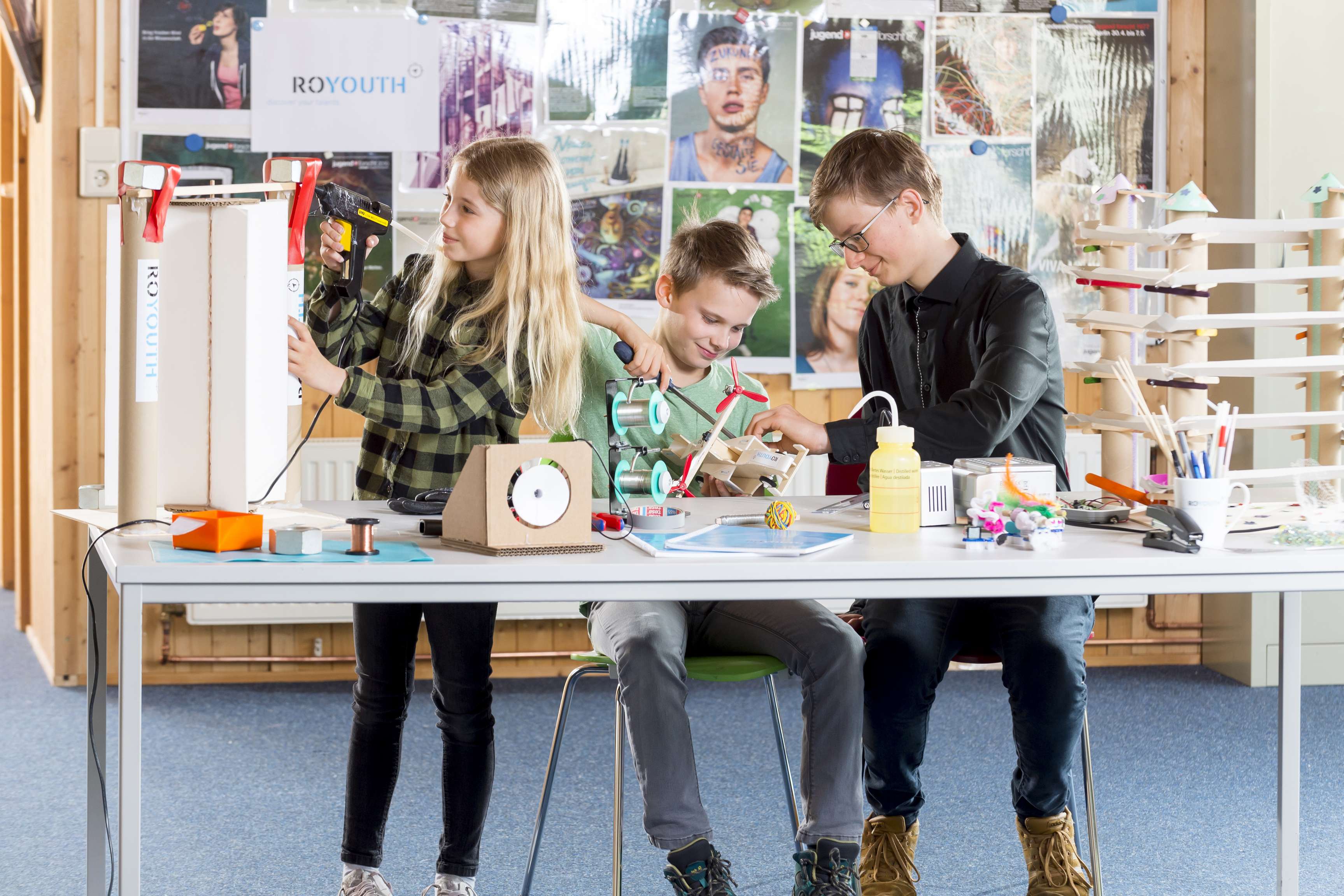 Three children conducting various experiments or making things at a table