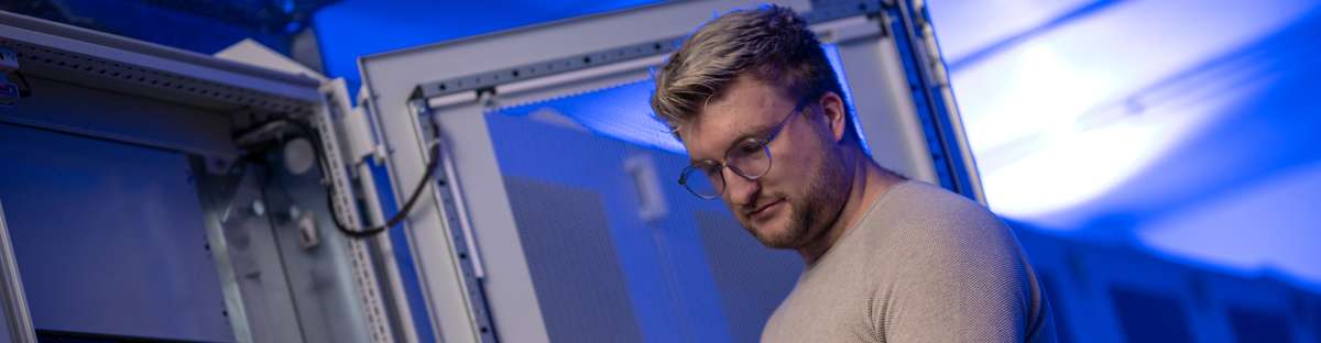 Mann arbeitet an einem Serverschrank in einem Serverraum.