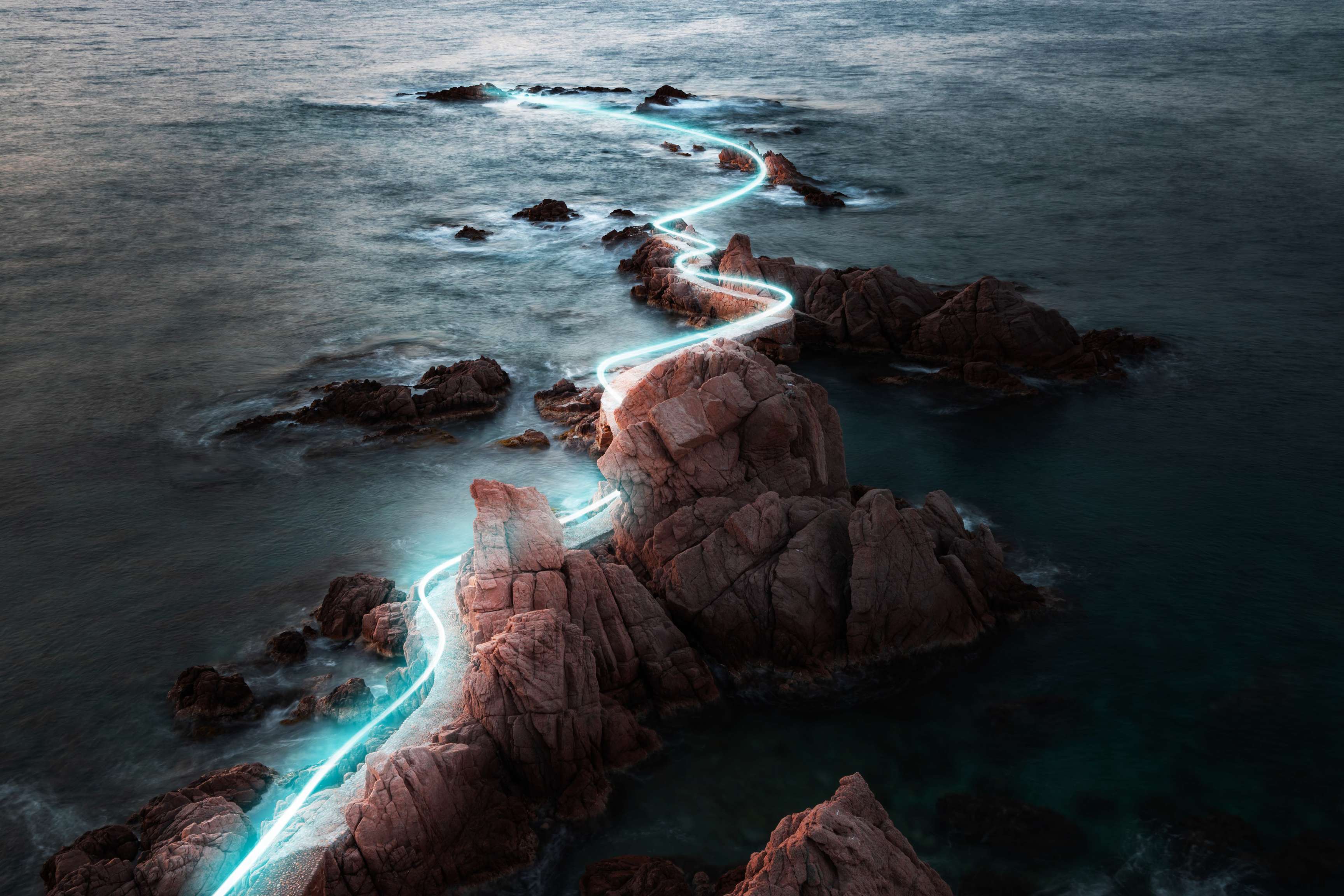 Rock formation in the sea with a curved light beam symbolizing an underwater pipeline.
