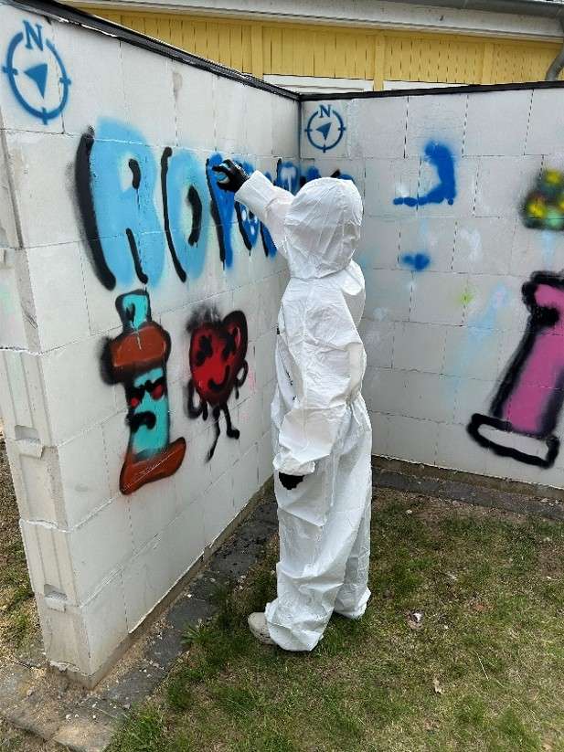 Ein Kind, das mit einer Sprühdose eine Wand bemalt.