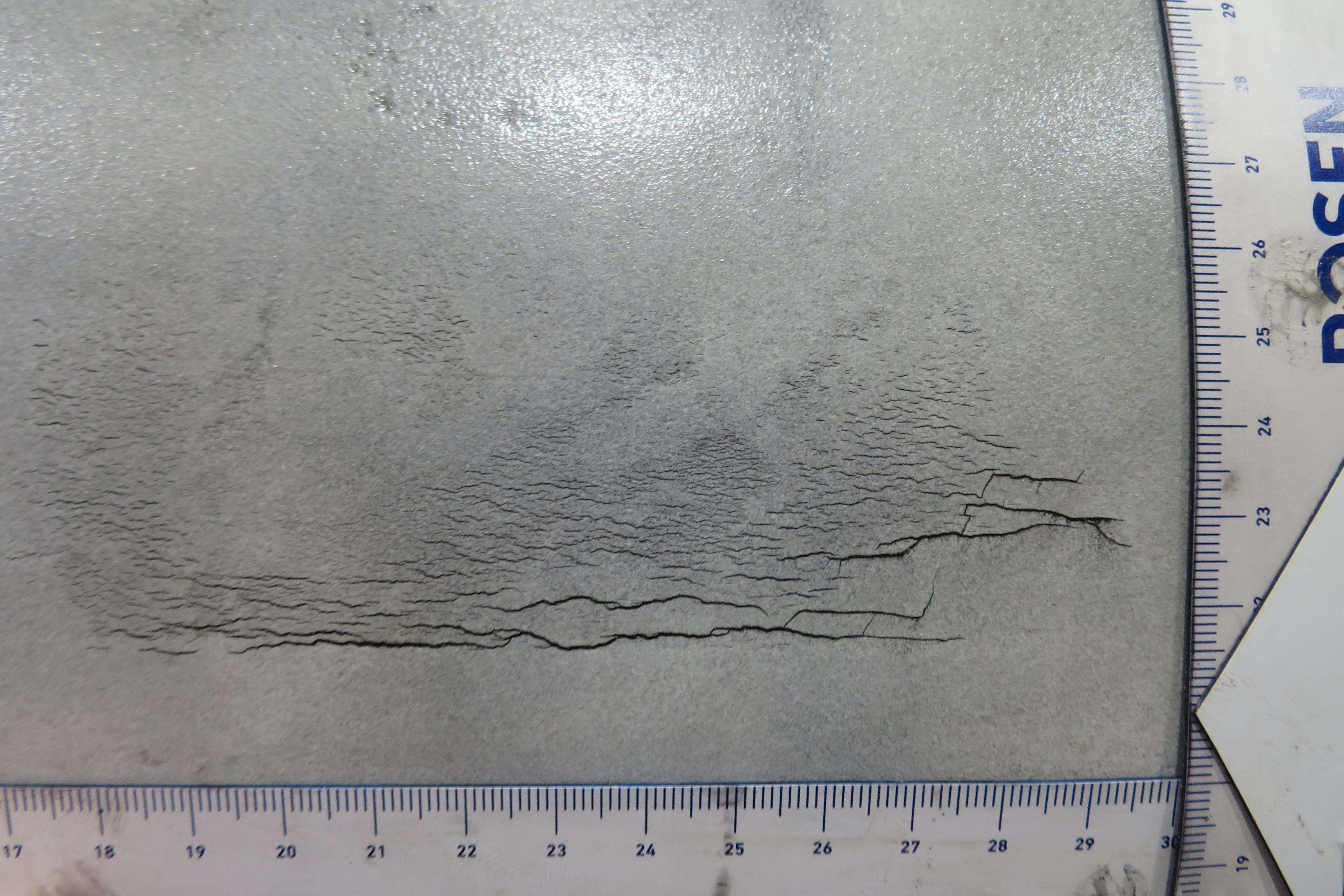 Detailed picture with cracks on a pipeline and measuring rulers on the side.