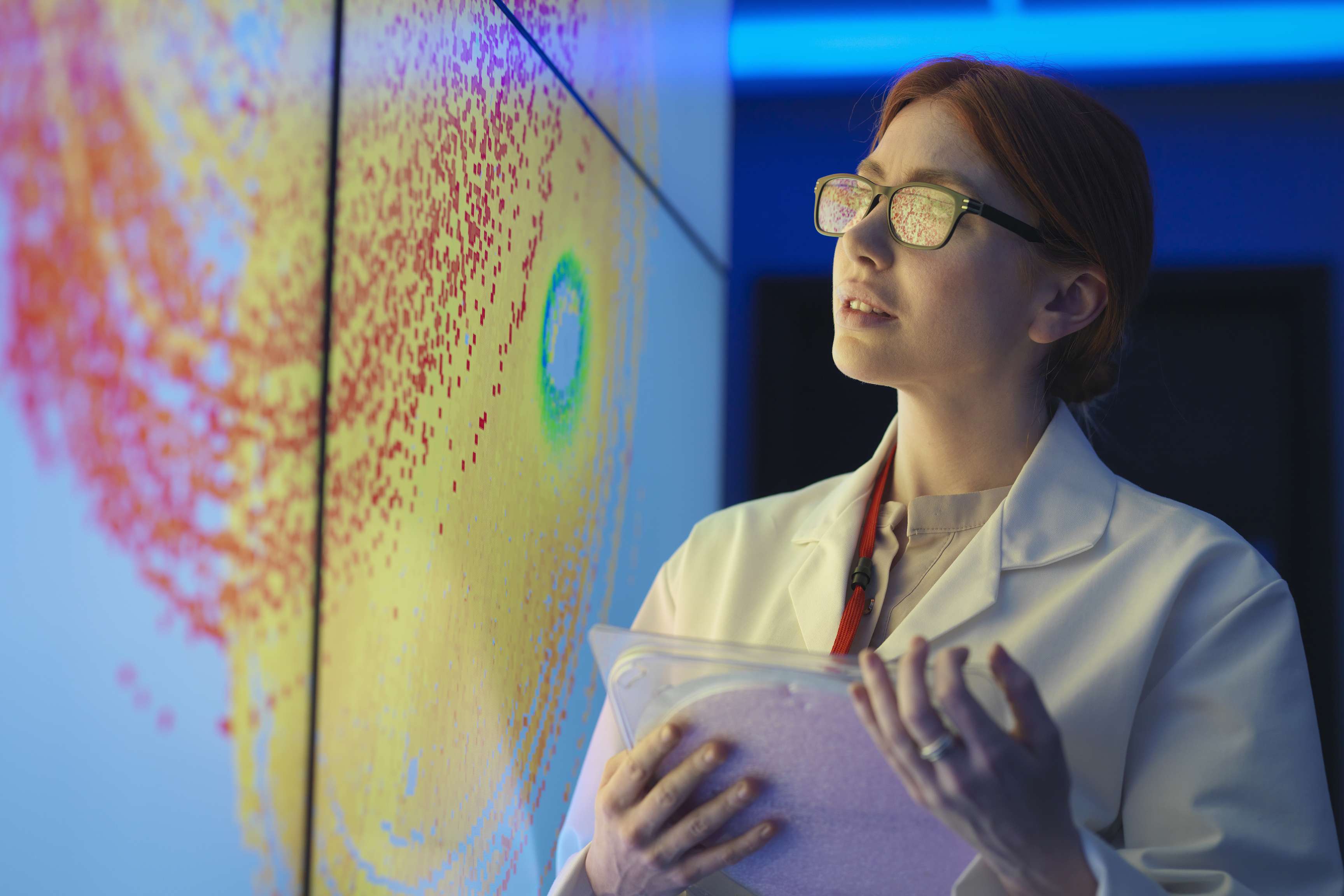 Woman studying a graphic representation of color dots and gradients on a screen.