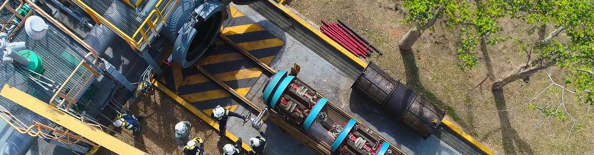 Aerial view of five engineers next to an open pipeline in front of which an in-line inspection tool is standing on a carrier and is to be launched into the pipeline. 