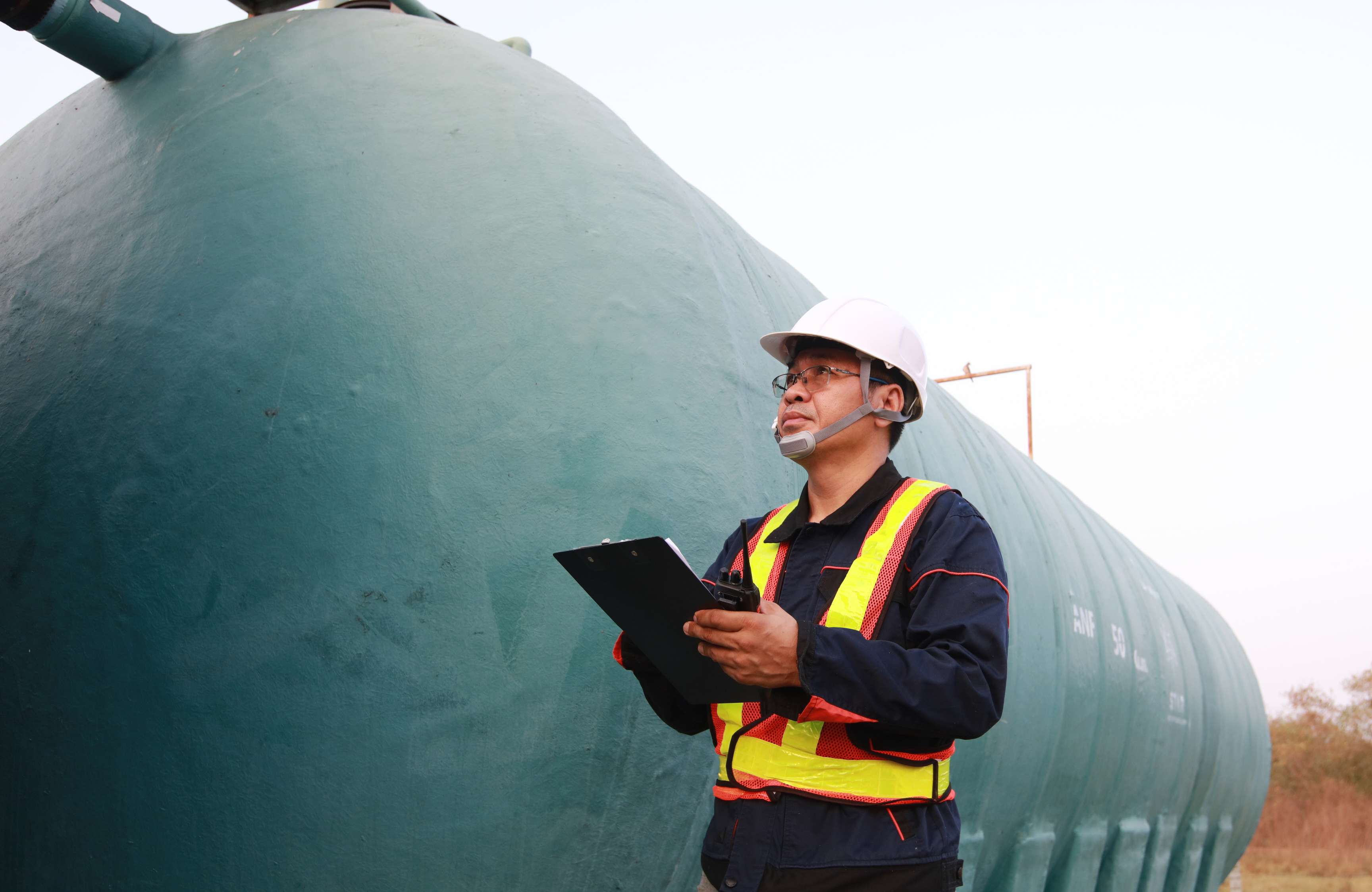 Field technicians standing at a pipeline with a checklist.