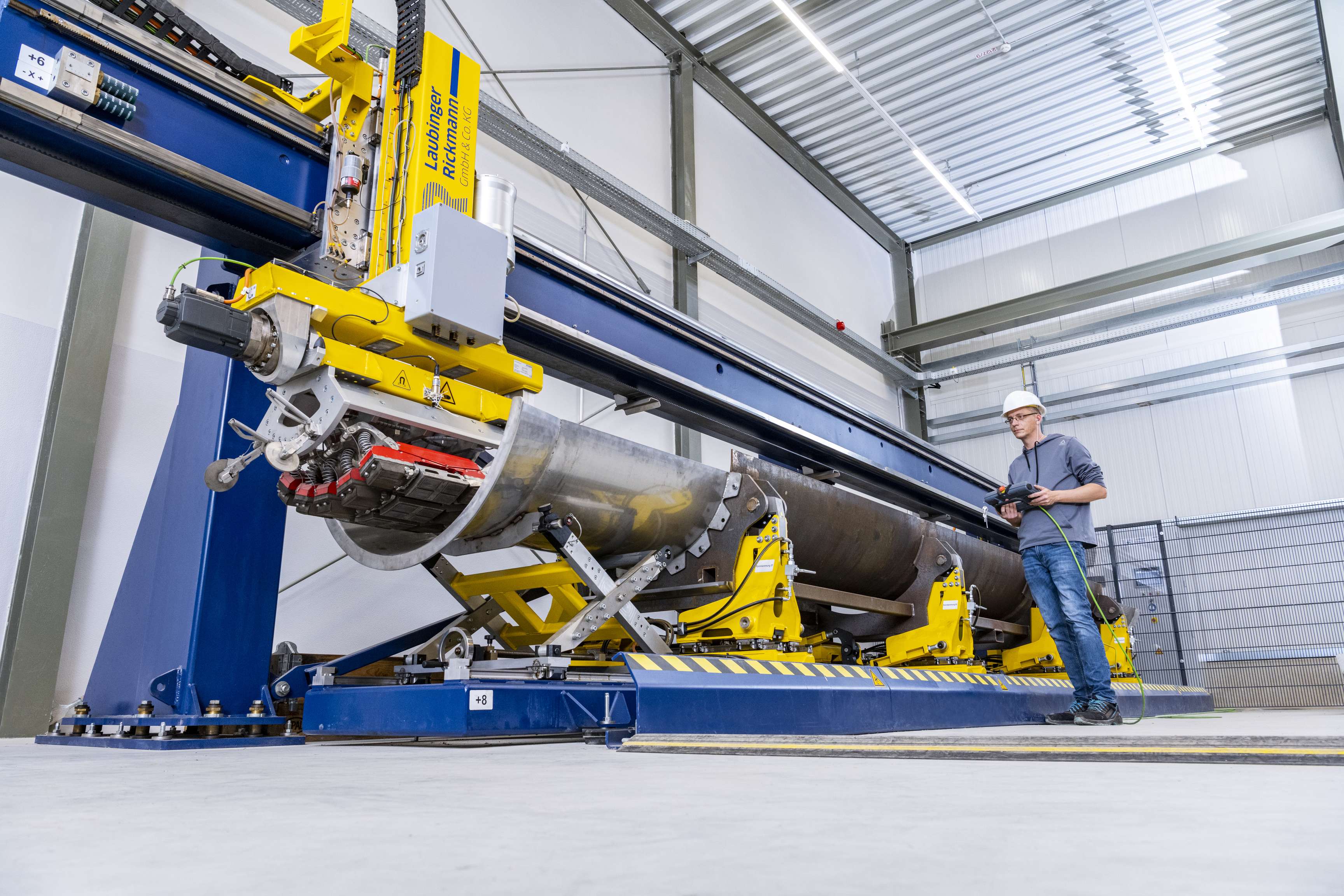 An employee operates a machine in which a tool passes through the open half of a pipeline.