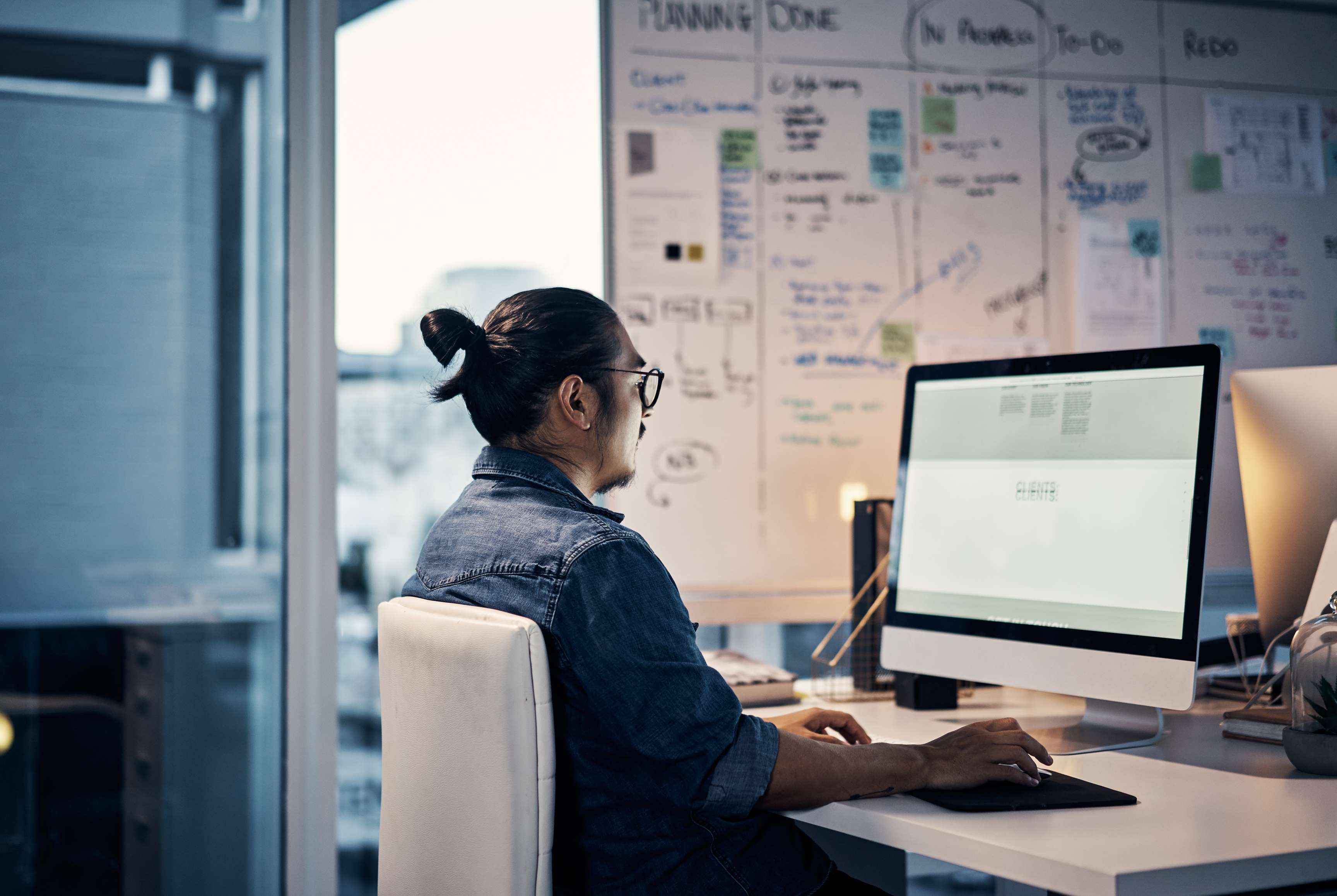 A man sits in front of two monitors with graphics and works.