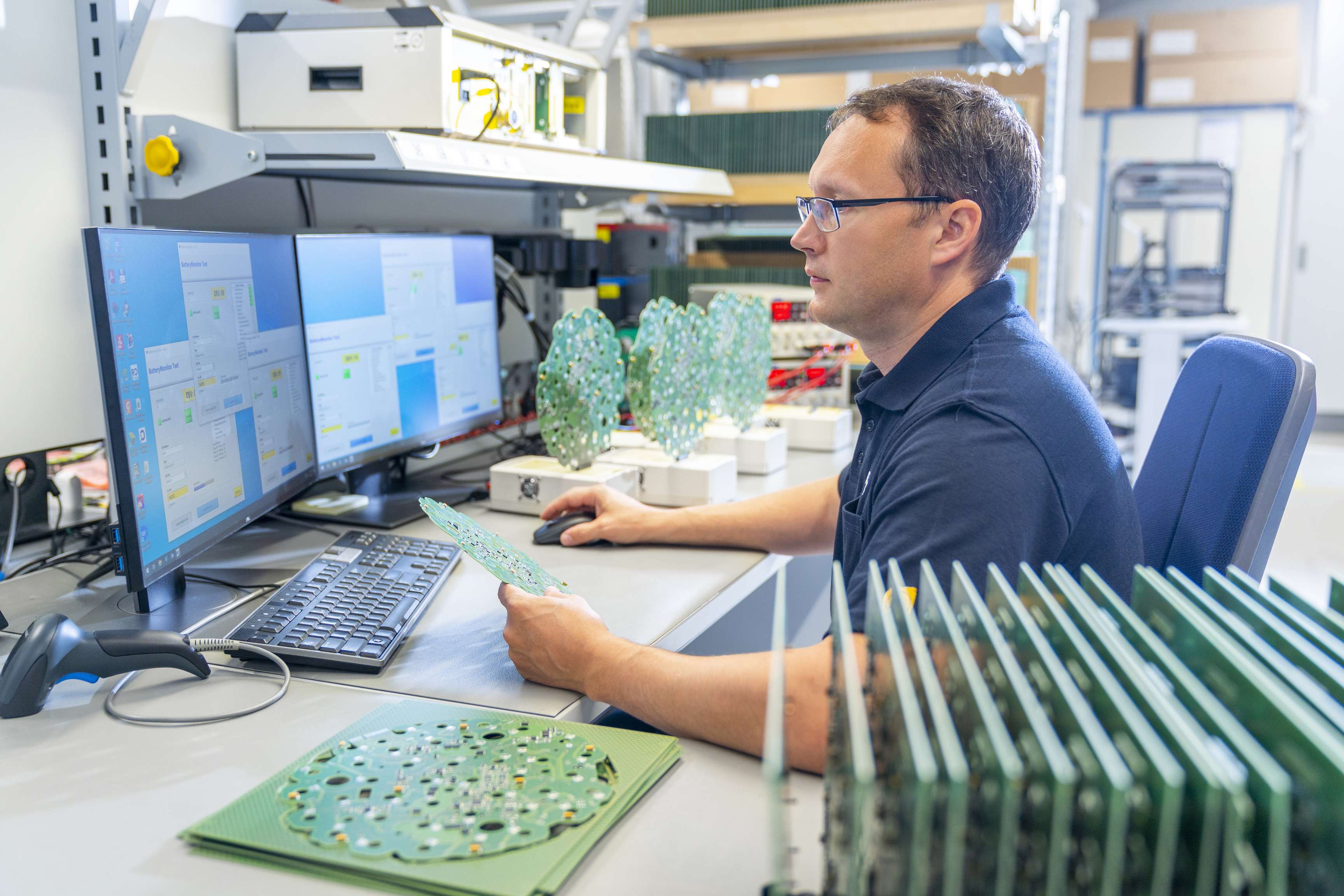Angestellter, der am Computer arbeitet und grüne Platten auf seinem Schreibtisch liegen hat.