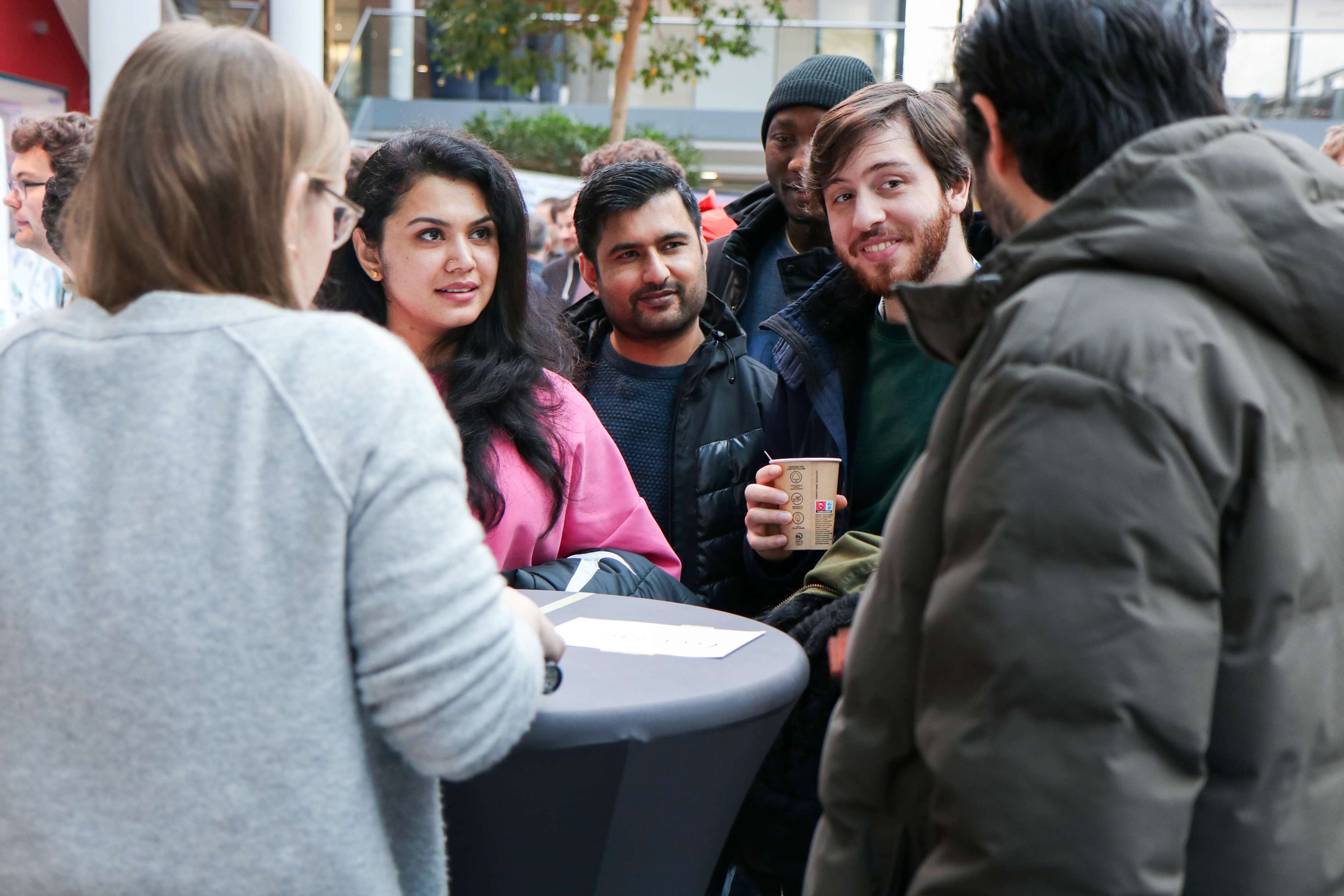 A group of people are chatting happily at a bar table.