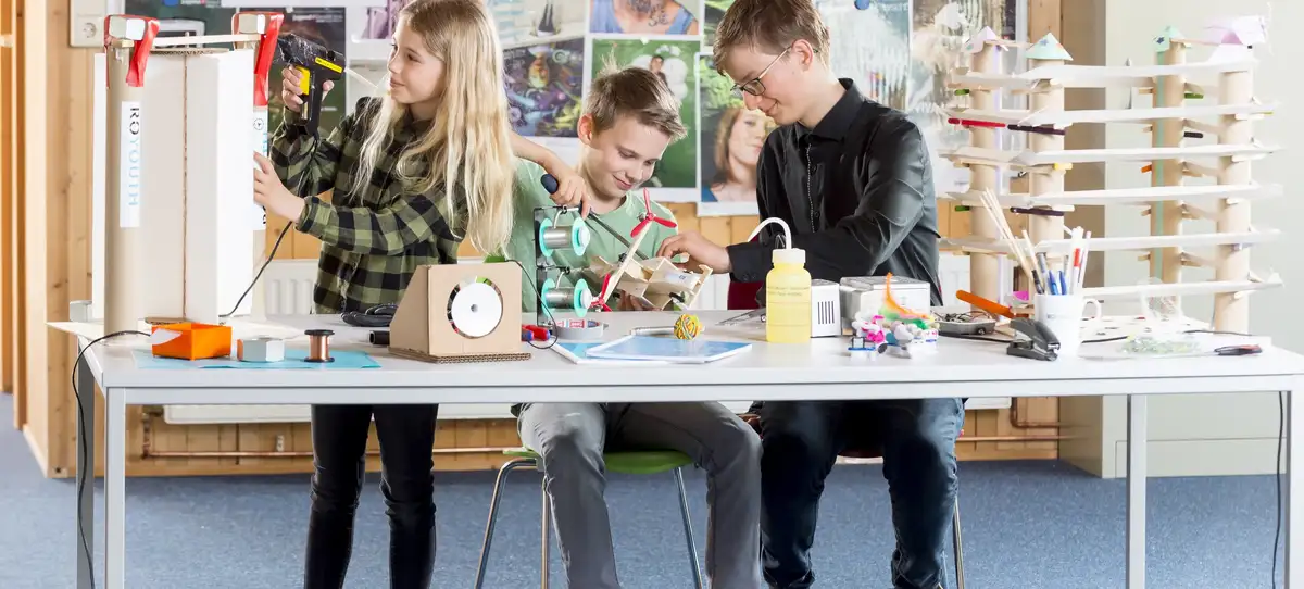 Three children conducting various experiments or making things at a table