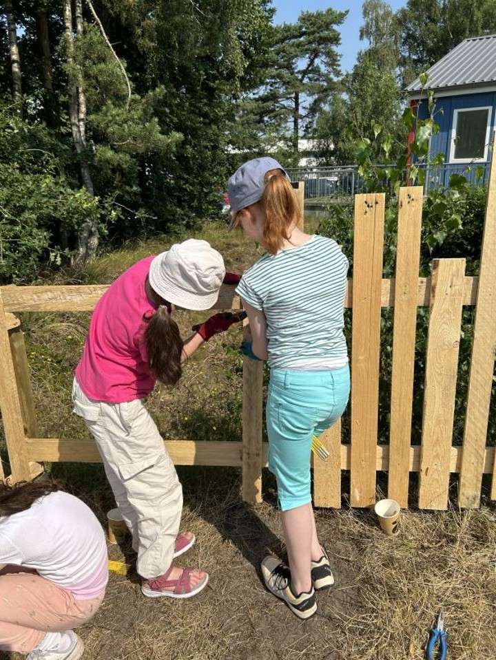 Kinder, die einen Zaun bauen.