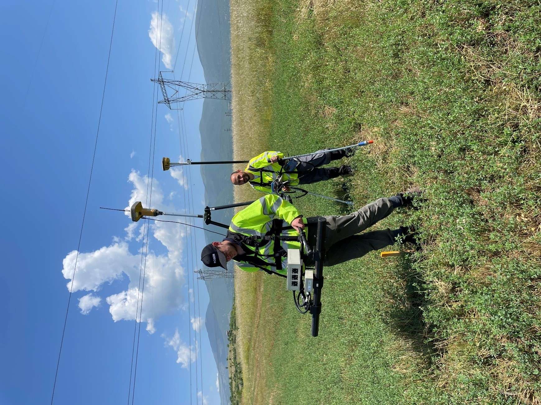 Two men in safety vests stand in a field and collect data for direct assessments. 