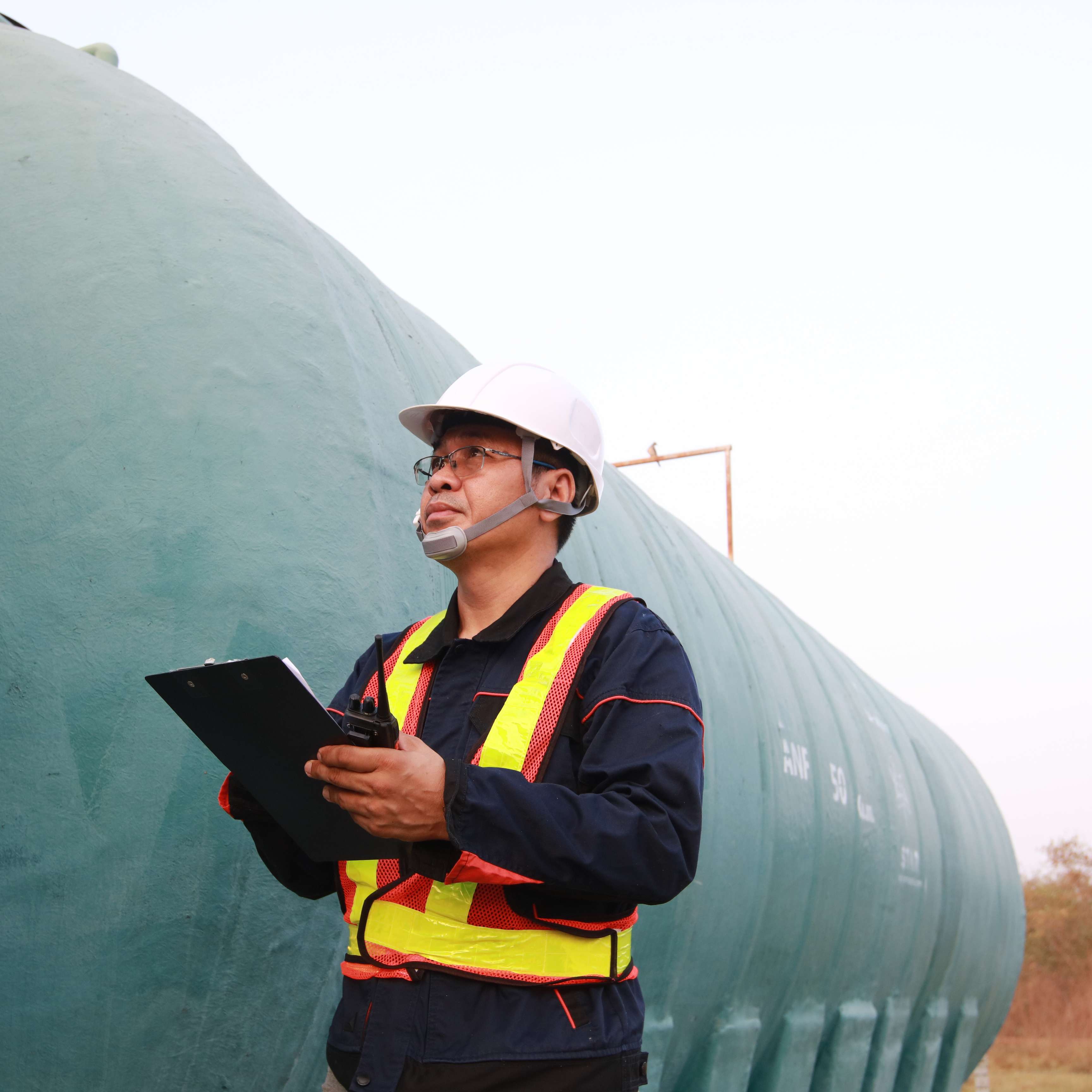 Field technicians standing at a pipeline with a checklist.