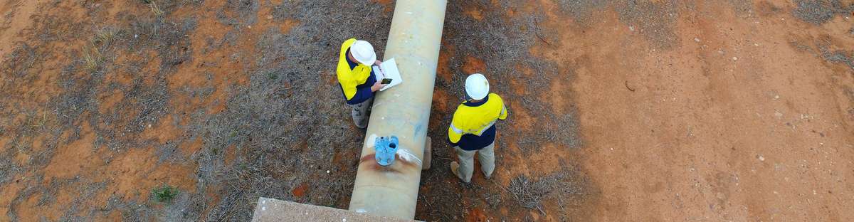 Aerial view of people standing at a pipline.