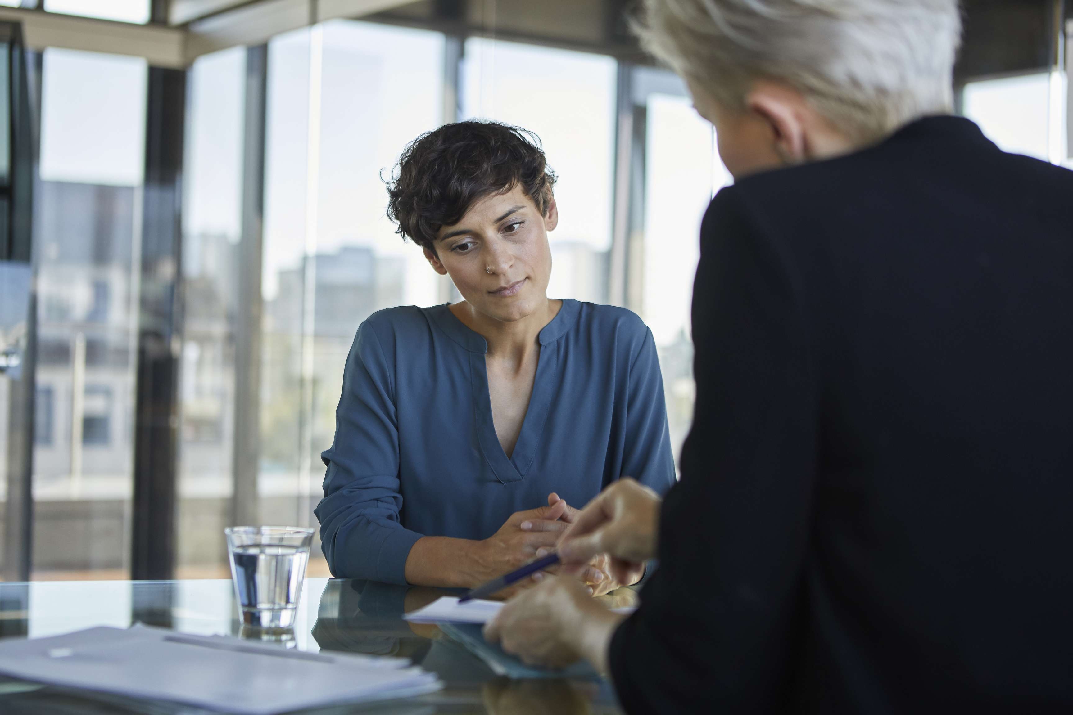 Two businesswomen talking at desk in office.