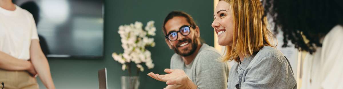Business woman talking to her colleagues during a meeting in a boardroom. Group of happy business people working together in a creative office.