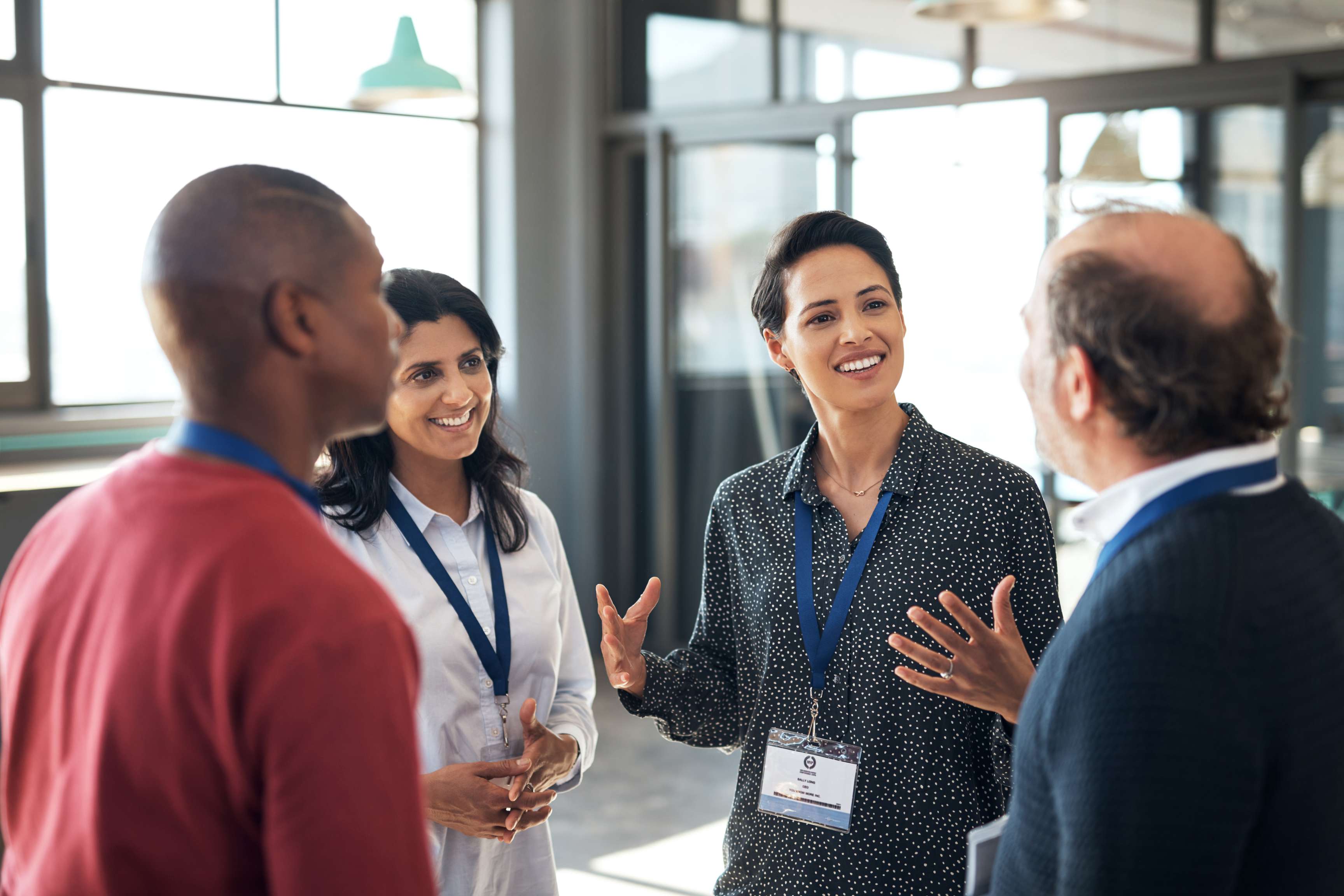 Photo of a group of business people standing in a circle at a conference, talking and networking.