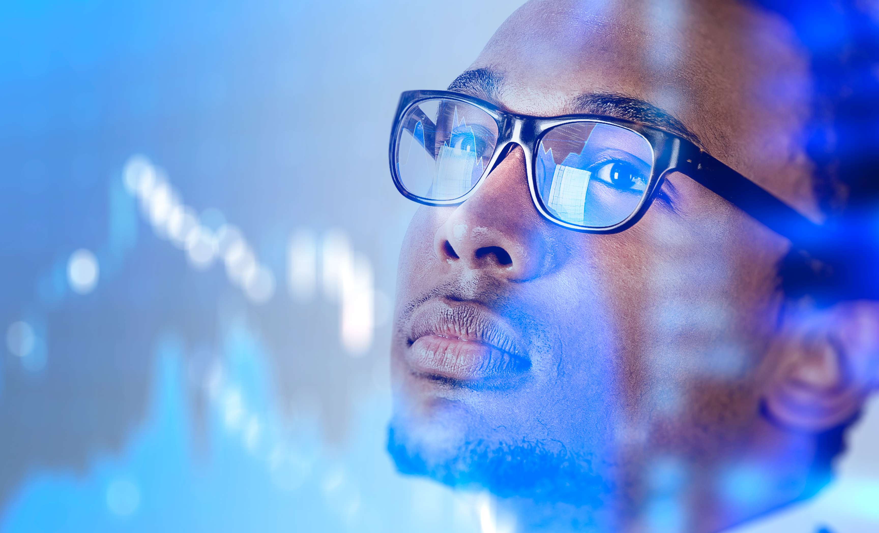 Employee looks at screen while it is reflected in his glasses.