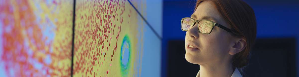Woman studying a graphic representation of color dots and gradients on a screen.