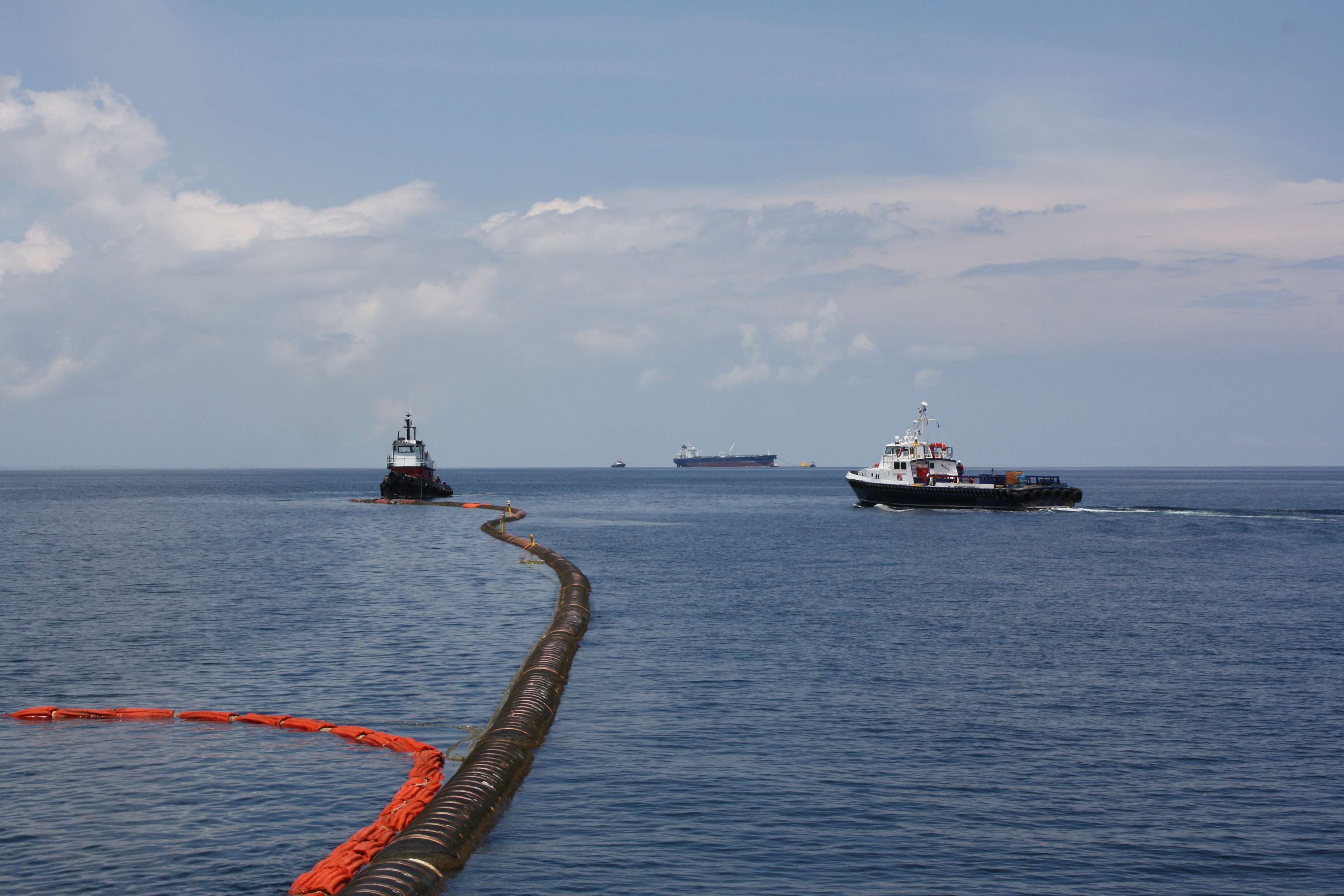 Black loading pipeline in the sea to a tanker in the background.