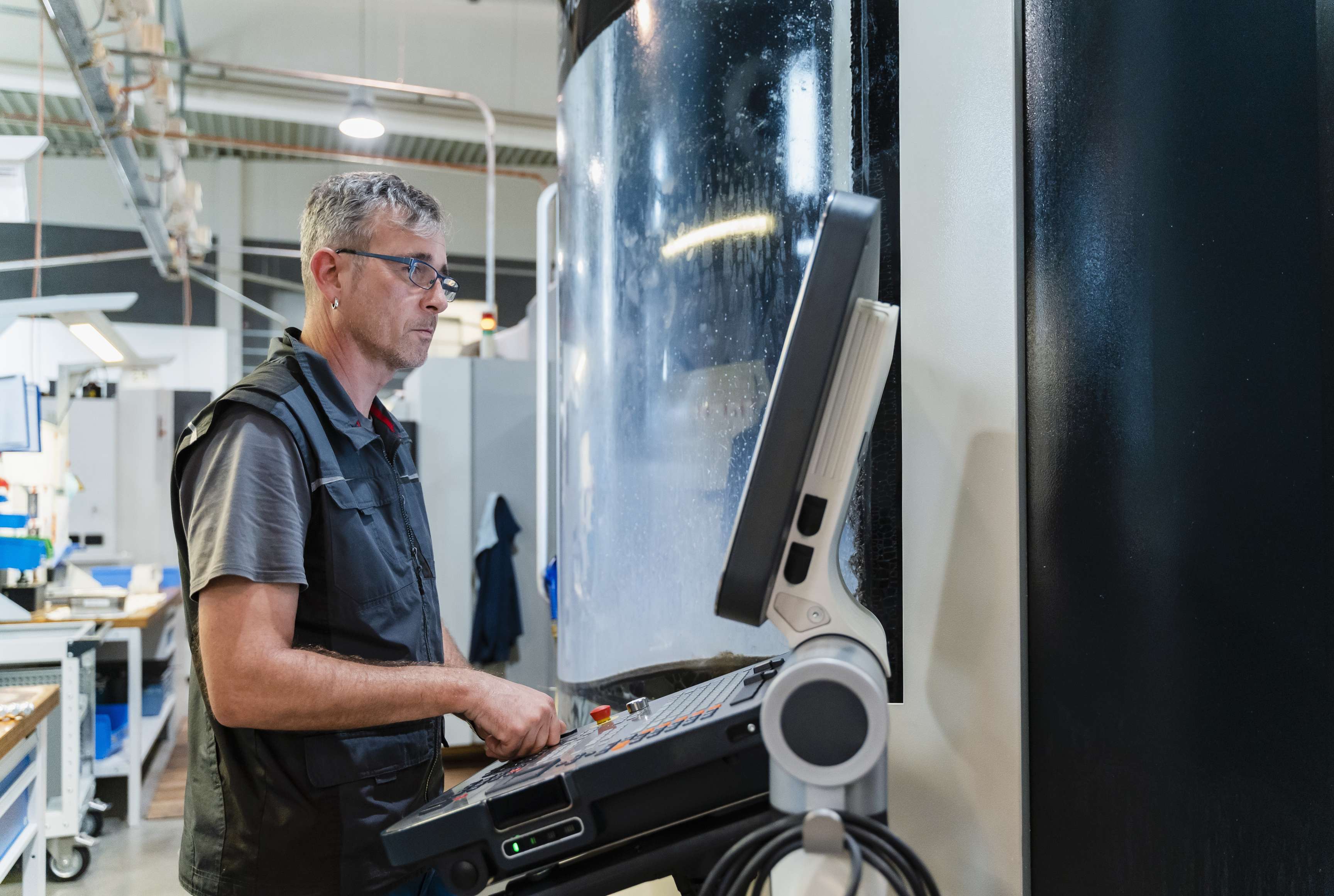 Man holding a paper in front of a machine in a production hall.