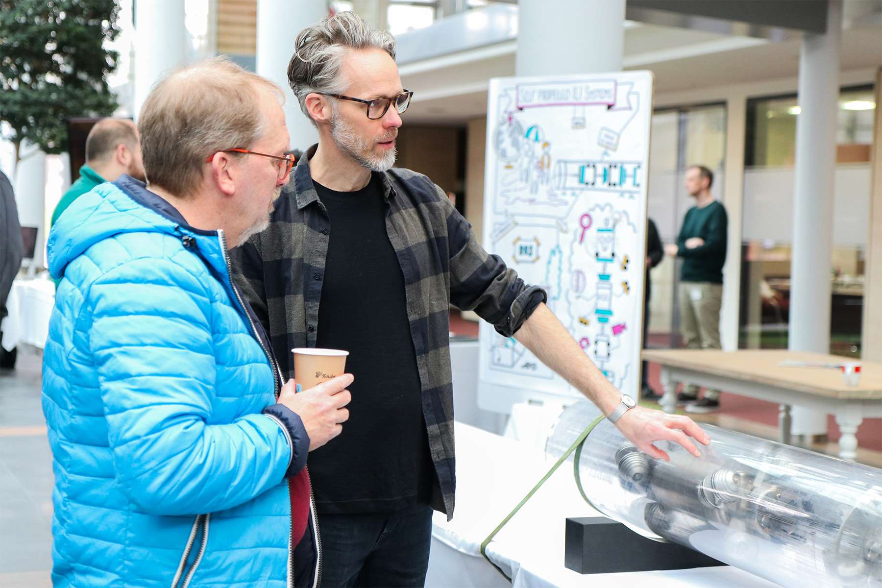 Two men standing in front of a tool that is exhibited during the Creation Day 2024.