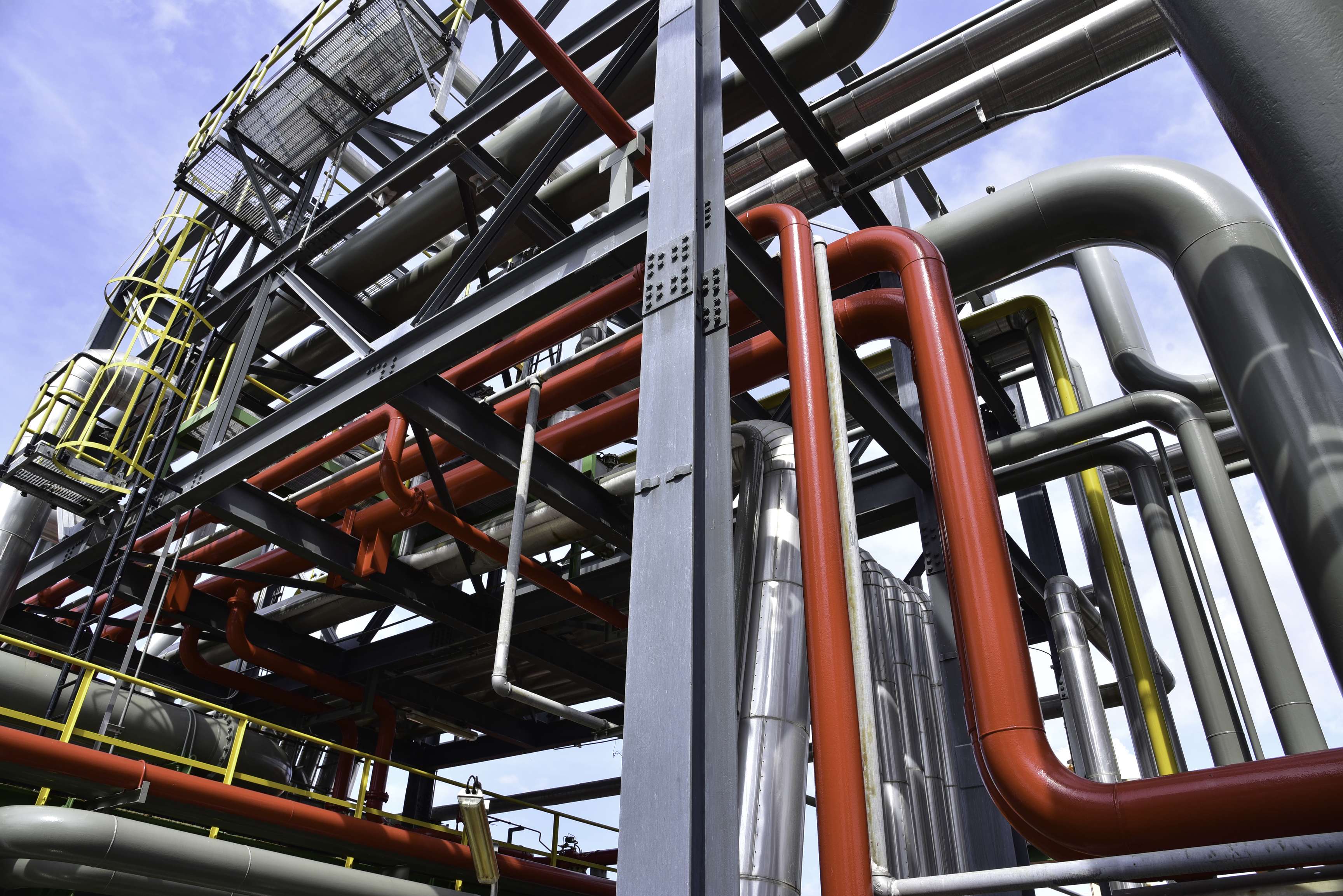 Frog's eye view: pipeline system with yellow and gray racks and gray, yellow and red pipelines.