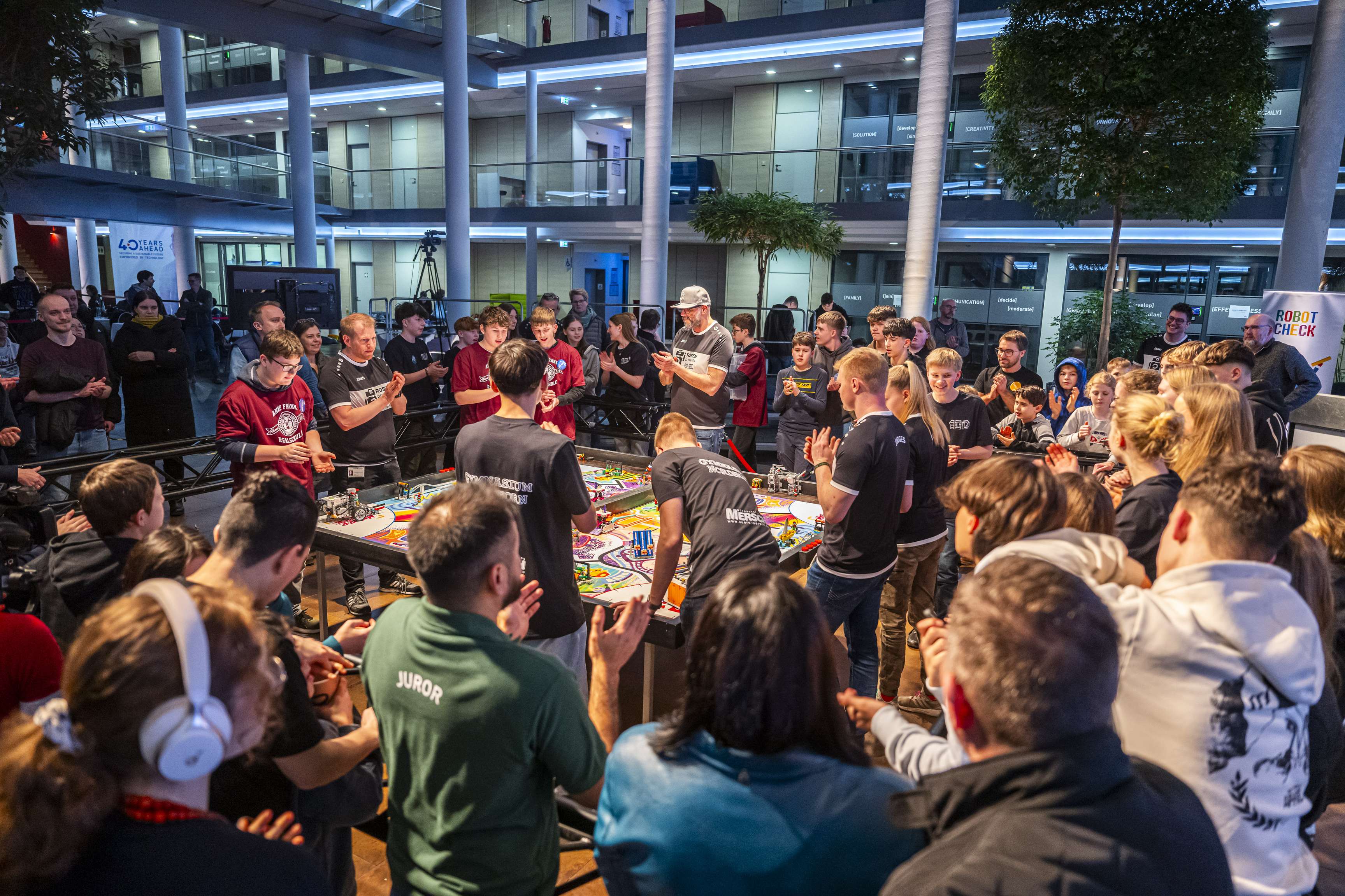 Many people stand around the tables where the Robot Games take place.