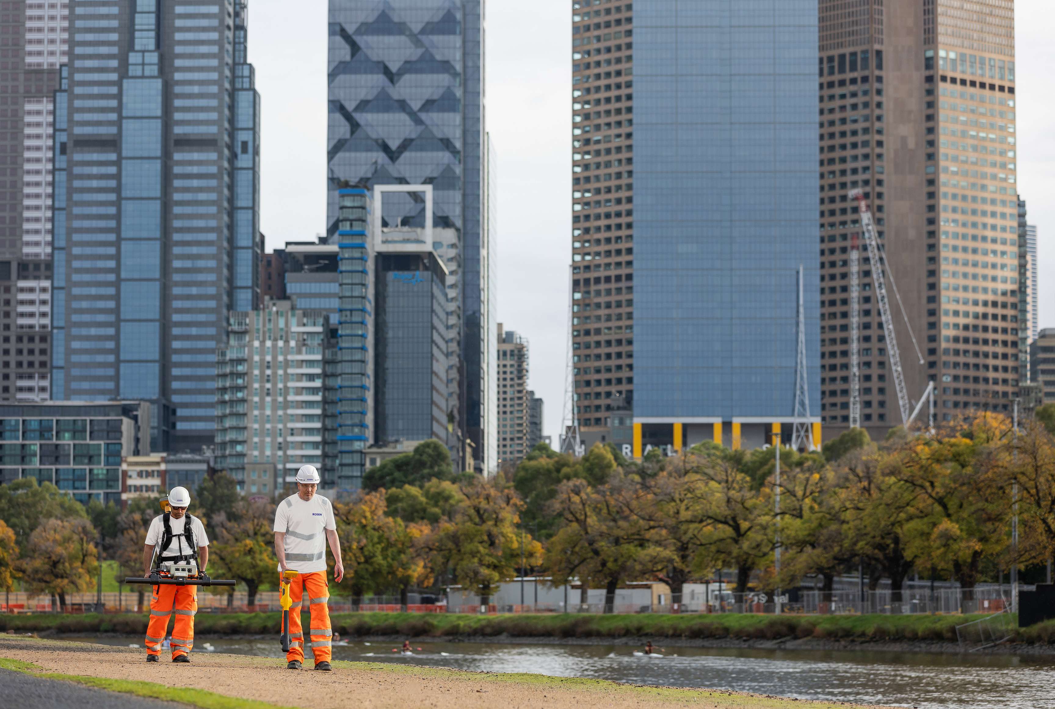 Two ROSEN employees during a Large Stand-Off Magnetometry (LSM) survey in front of a skyline.