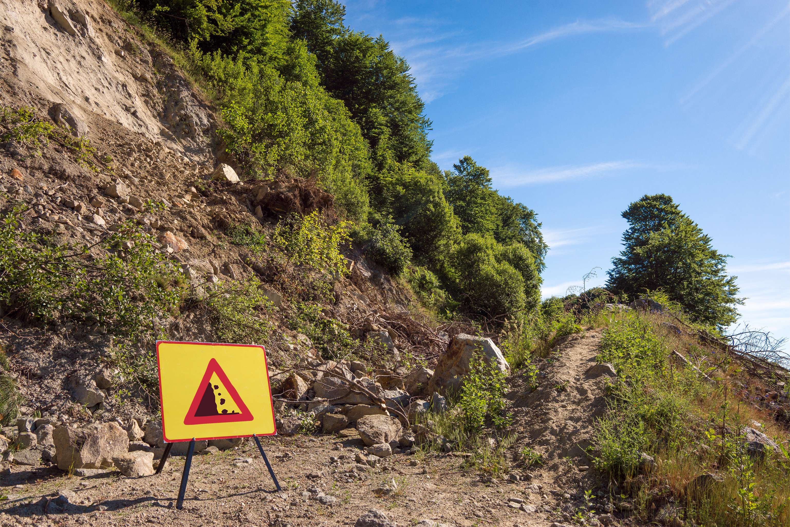 Sign with warning of falling rocks at the end of a road.