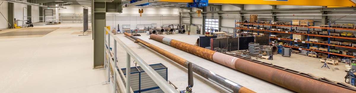 Section of a hall in which two pipelines were assembled from different pieces and a large shelf in the background.