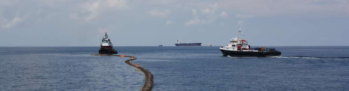 Black loading pipeline in the sea to a tanker in the background.