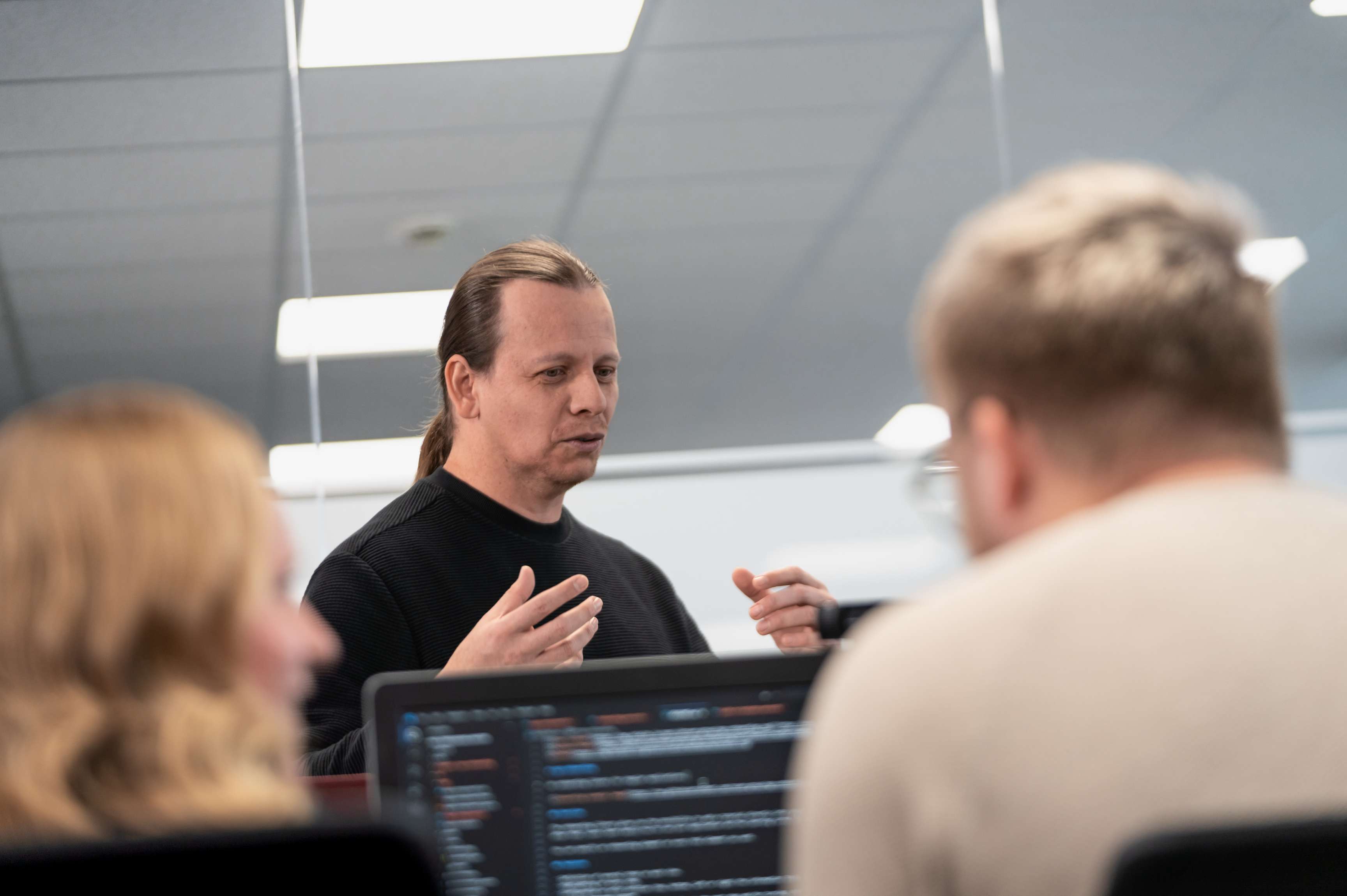 ROSEN colleagues sitting or standing in front of screens in an office environment.