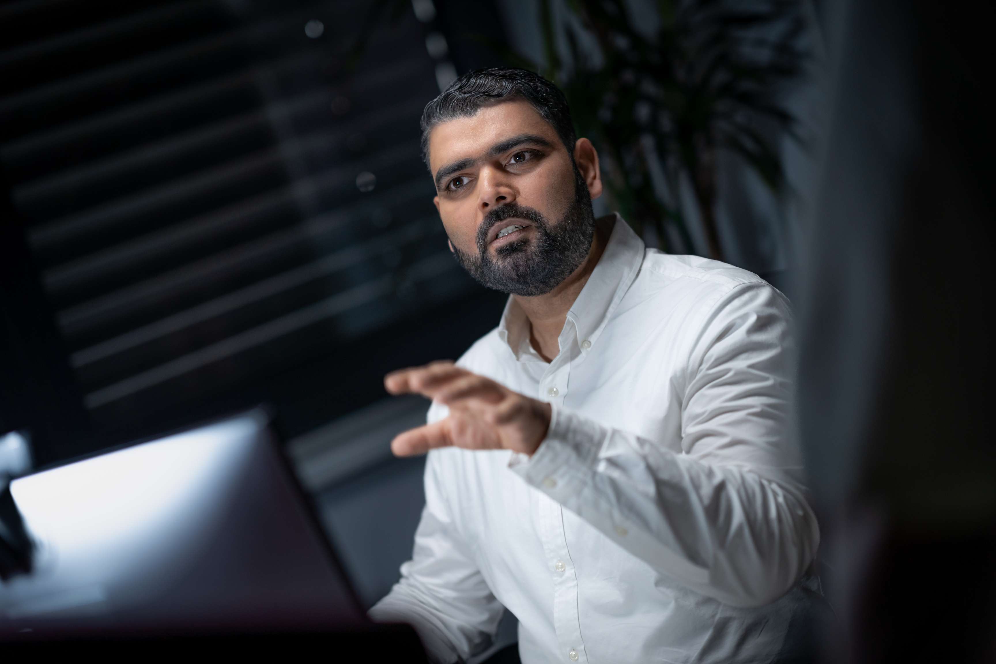 Ein Mann sitzt an einem Schreibtisch und erklärt etwas.