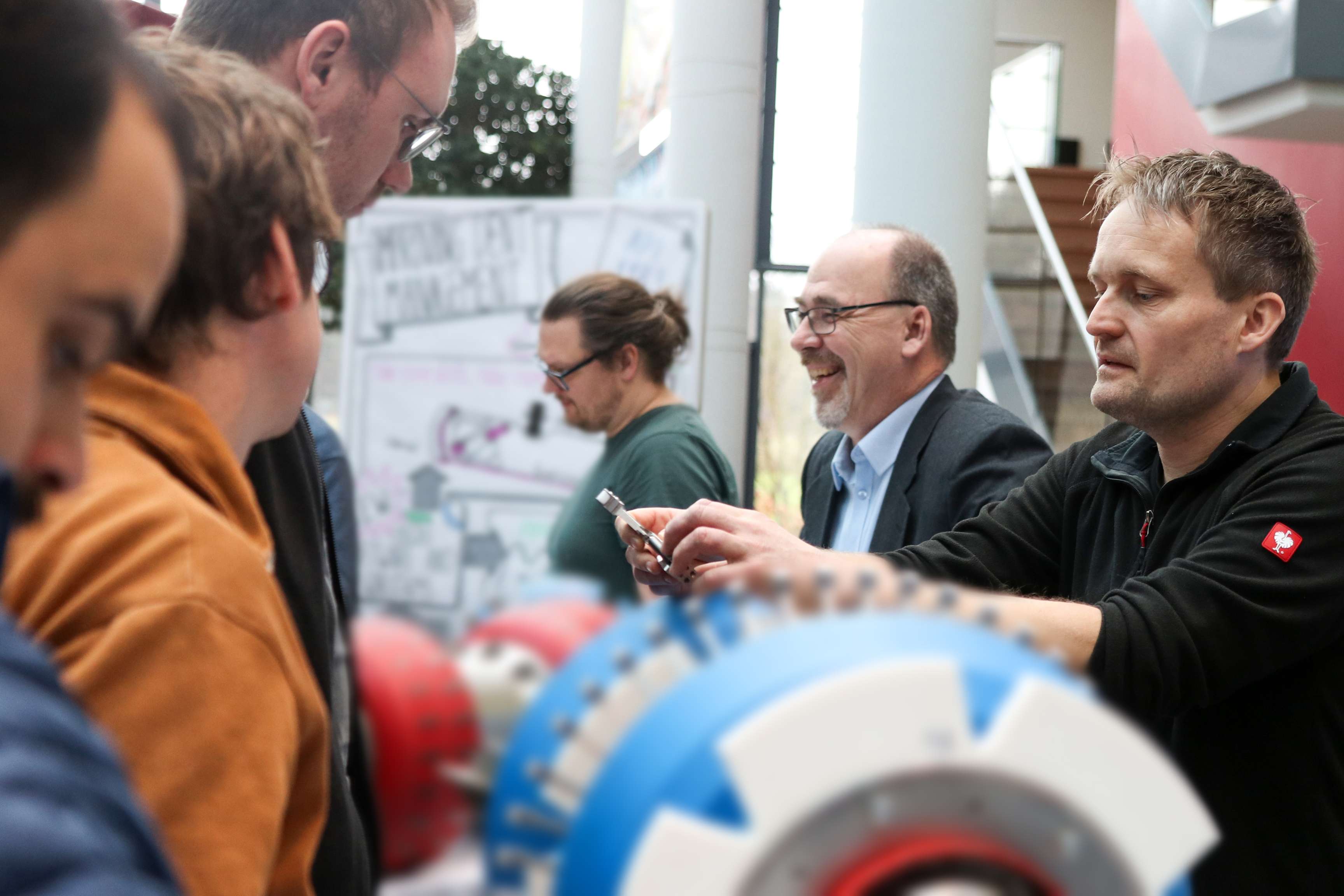 A man is explaining a small tool to a group of people.